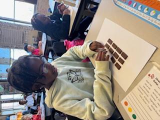 a female student uses Hershey's to demonstrate fractions