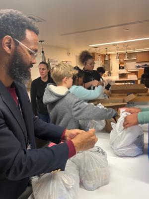 a student and teacher fill bags for unhoused people during an advisory service project