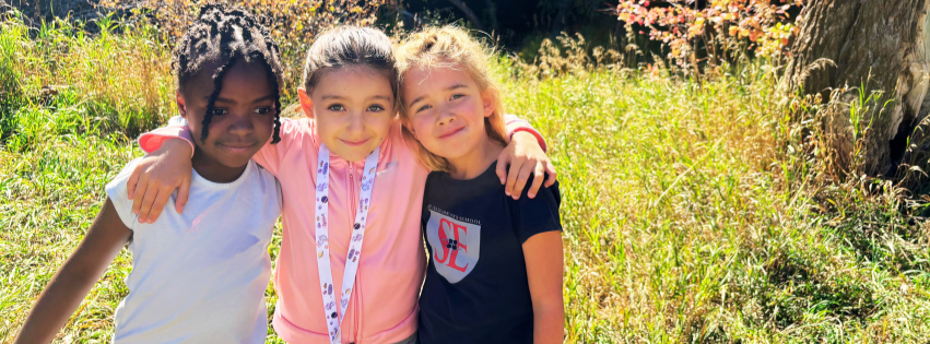 Three first grade girls smile at the camera at St. Elizabeth's School