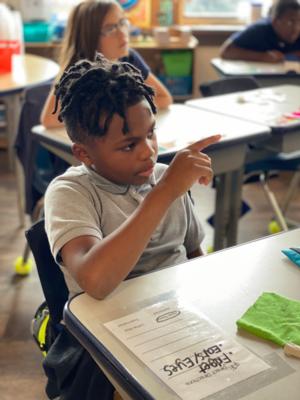 a student points to something at the front of the class