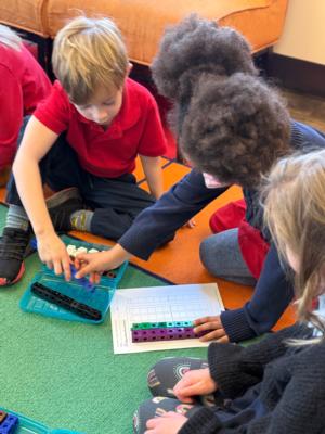 a small boy and girl work on a math problem using cubes