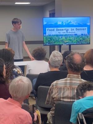 an 8th grade boy presents his capstone on Food Deserts in Denver