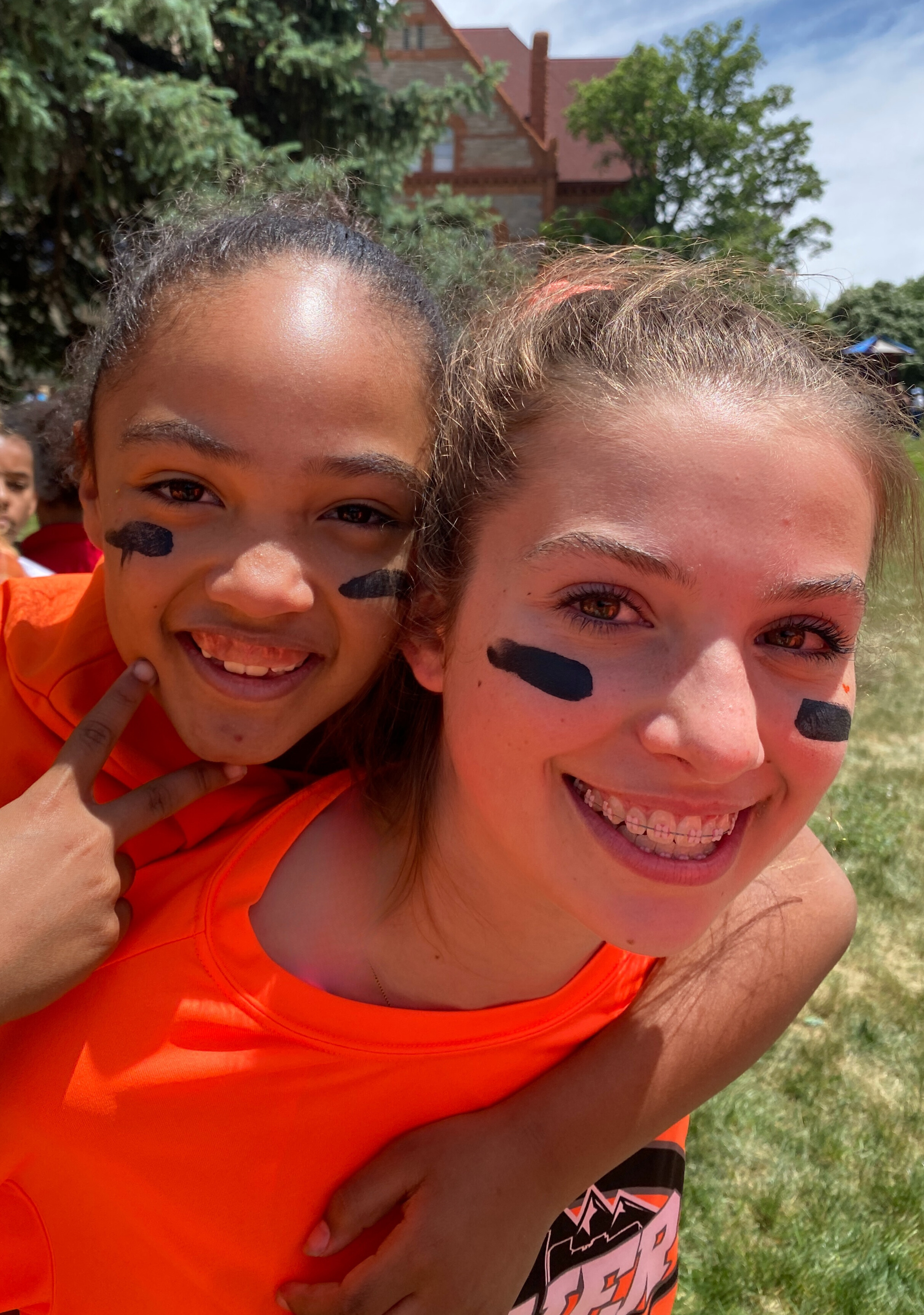 two girls smiling at the camera, the older girls carries the younger