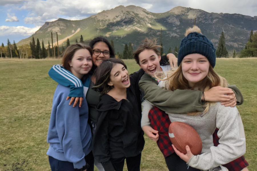 middle school girls smile at the camera with mountains in the background