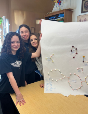 Three girls hold up models off different molecules