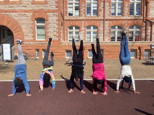 several students perform handstands facing away from the camera
