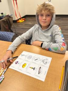 a blonde boy looks up from a Spanish worksheet